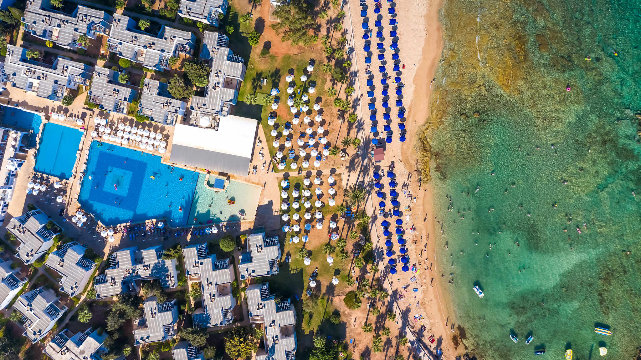 Blick auf einen Strand mit blauen Liegen und Sonnenschirmen